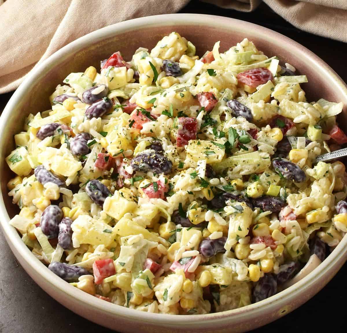 Side view of pineapple corn salad in rustic pink bowl.