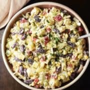 Top down view of pineapple salad in pink bowl with spoon.