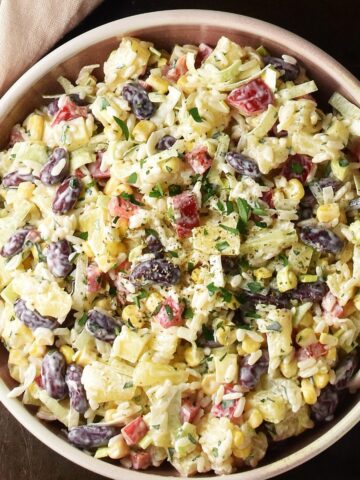 Top down view of pineapple salad in pink bowl with spoon.