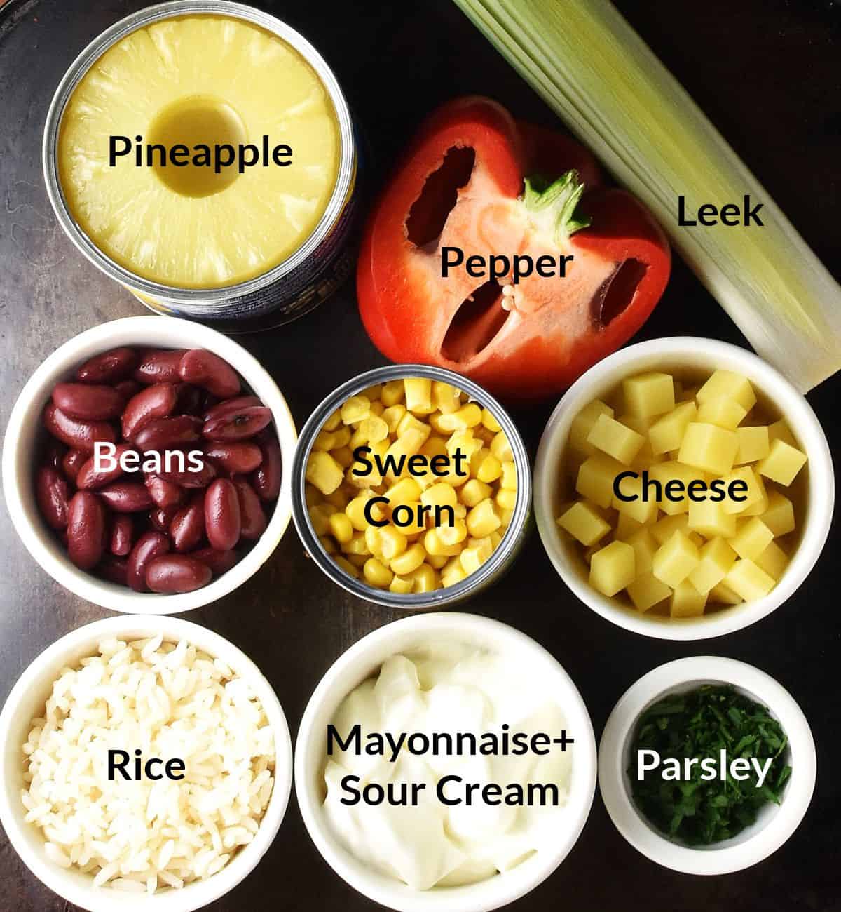 Top down view of pineapple salad ingredients in small, labelled dishes.