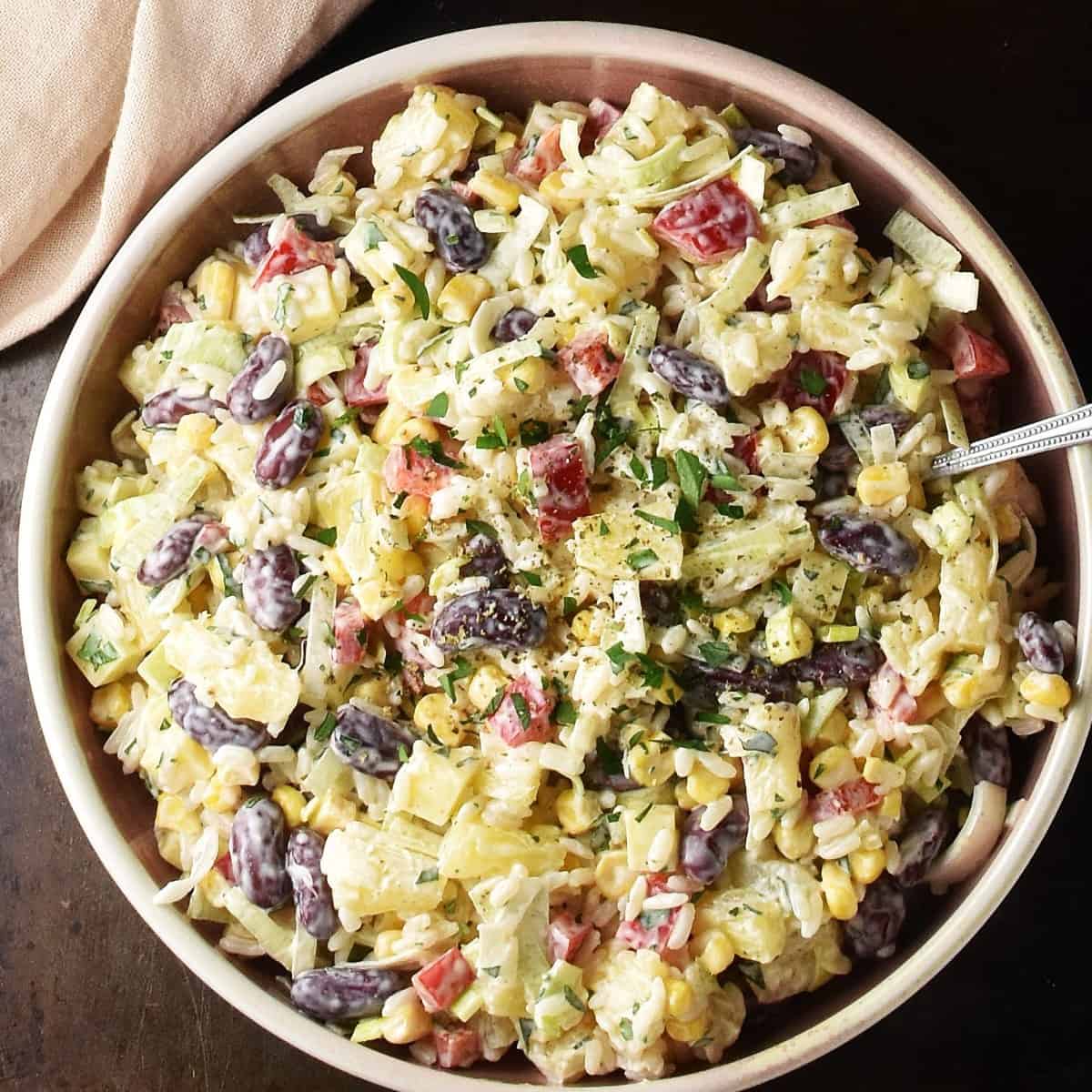 Top down view of pineapple salad in pink bowl with spoon.
