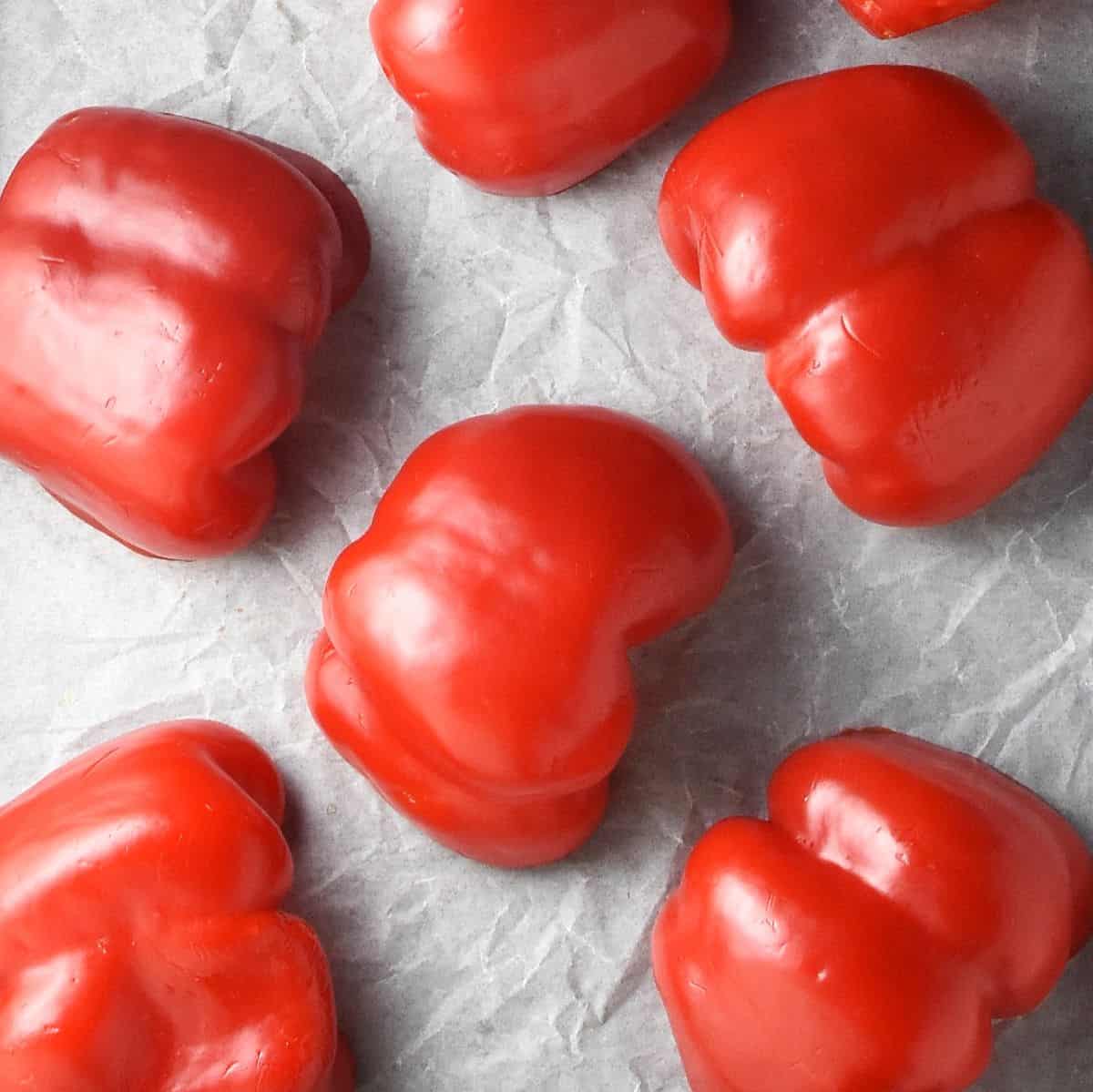 Halved red peppers on top of parchment paper.
