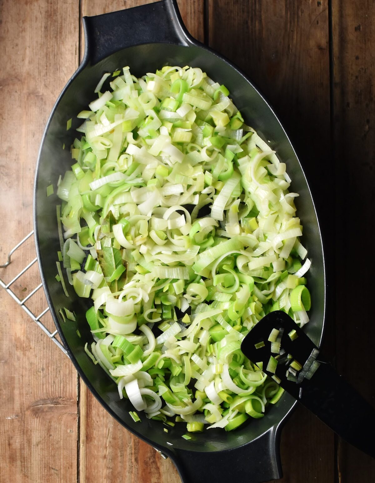 Fried chopped leeks in large oval, black dish. 