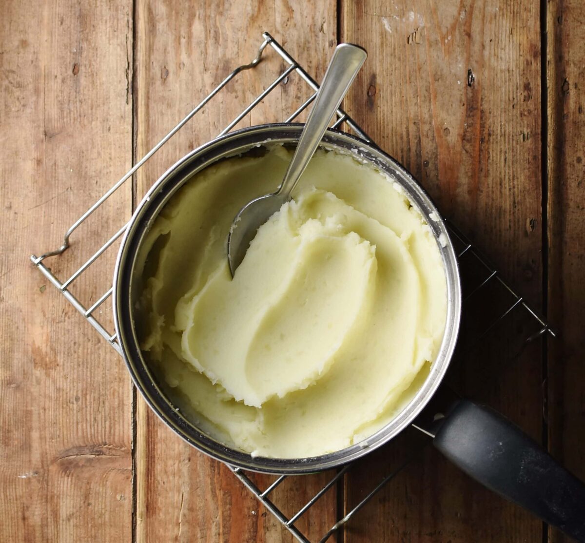 Mashed potatoes with spoon in pot.