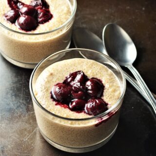 Quinoa pudding with fruit compote in 2 dishes with spoons in background.