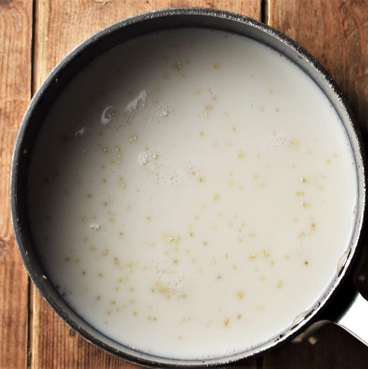 Quinoa with milk in saucepan.