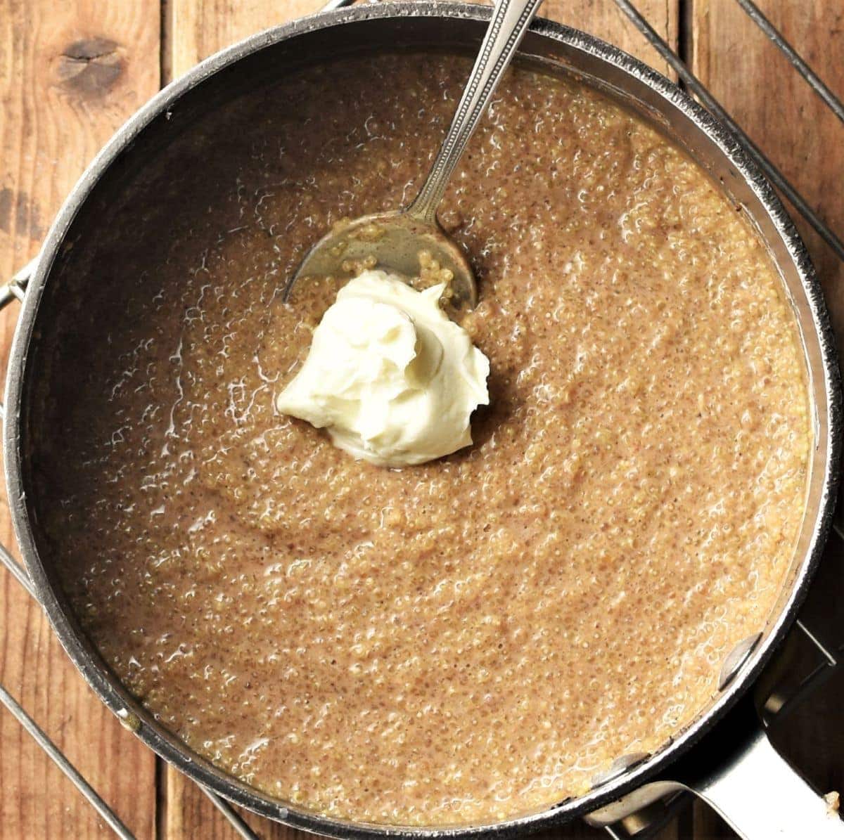 Creamy quinoa pudding with dollop of mascarpone in pot with spoon.