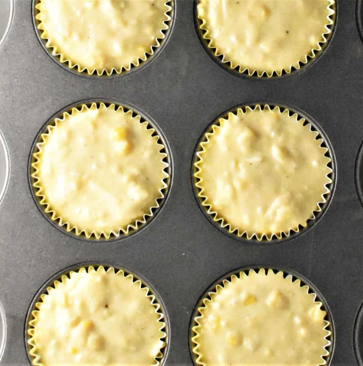 Sweetcorn muffin batter in cases inside muffin pan.