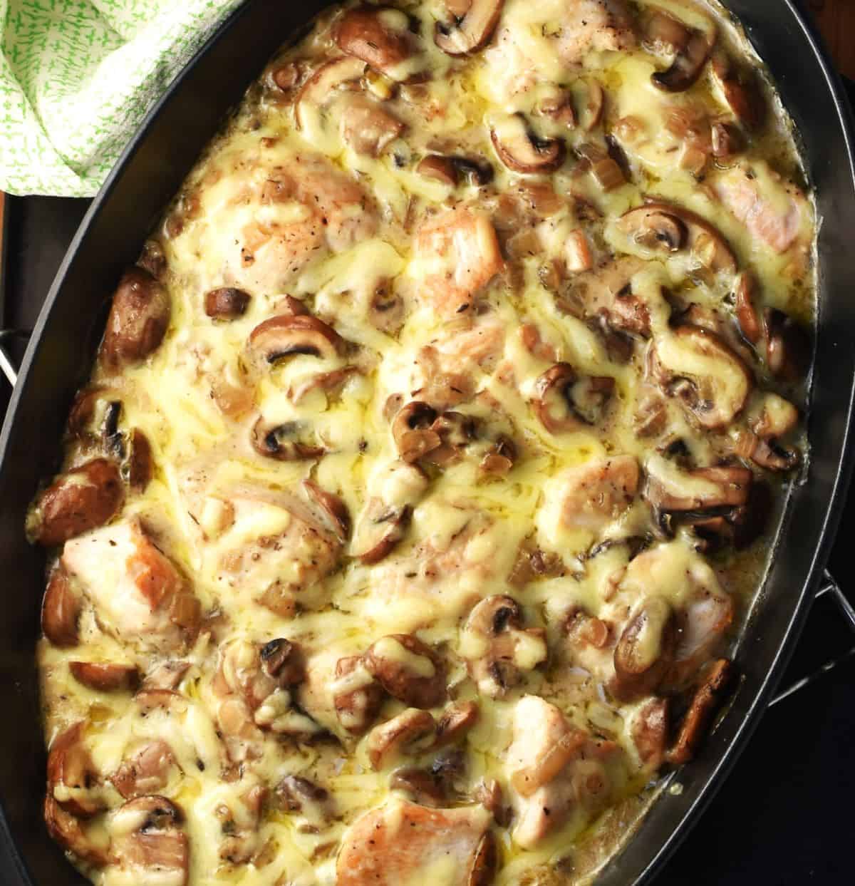 Baked chicken mushroom casserole in black oval dish.