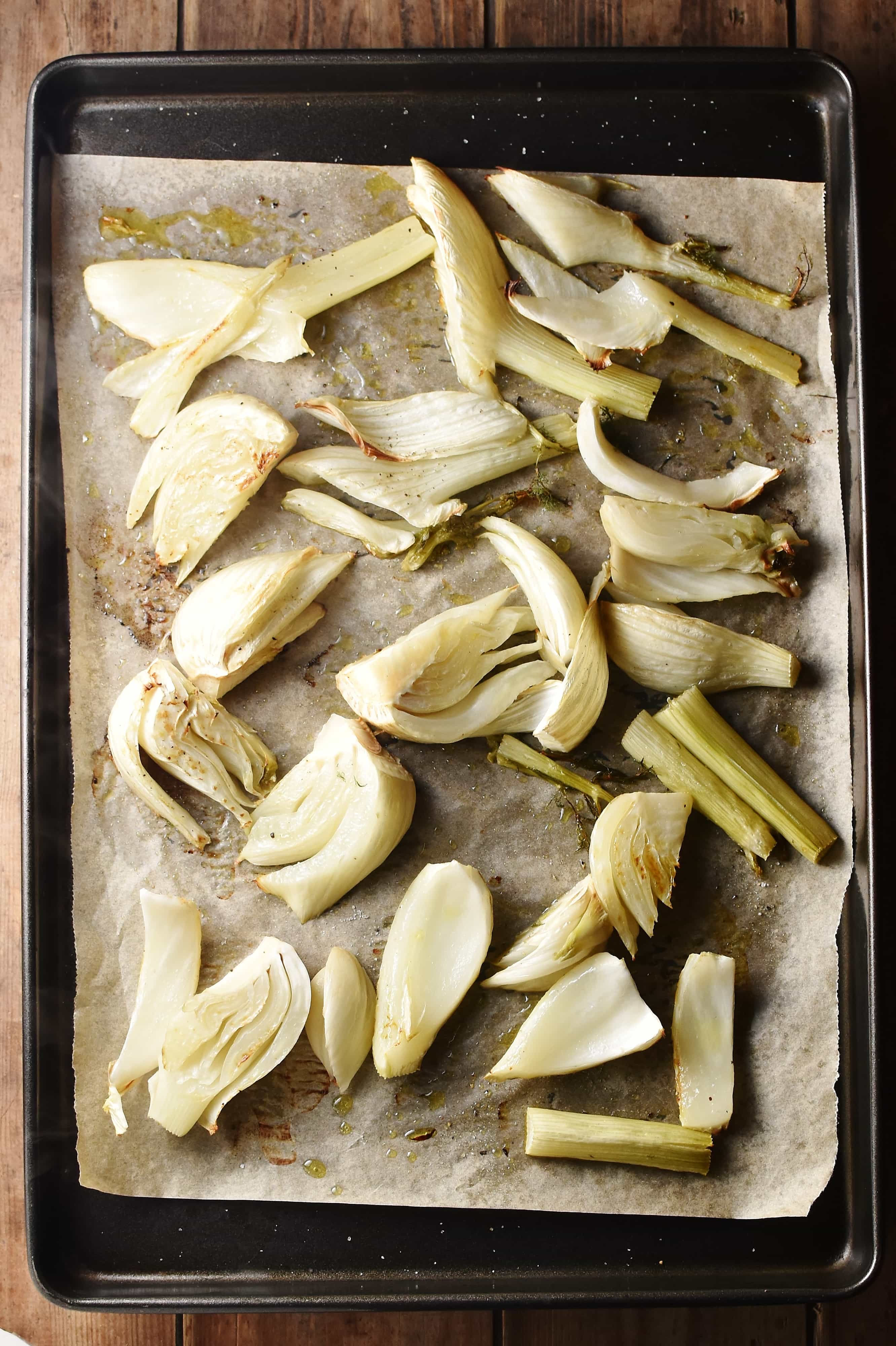 Roasted fennel pieces on top of baking sheet lined with parchment paper.