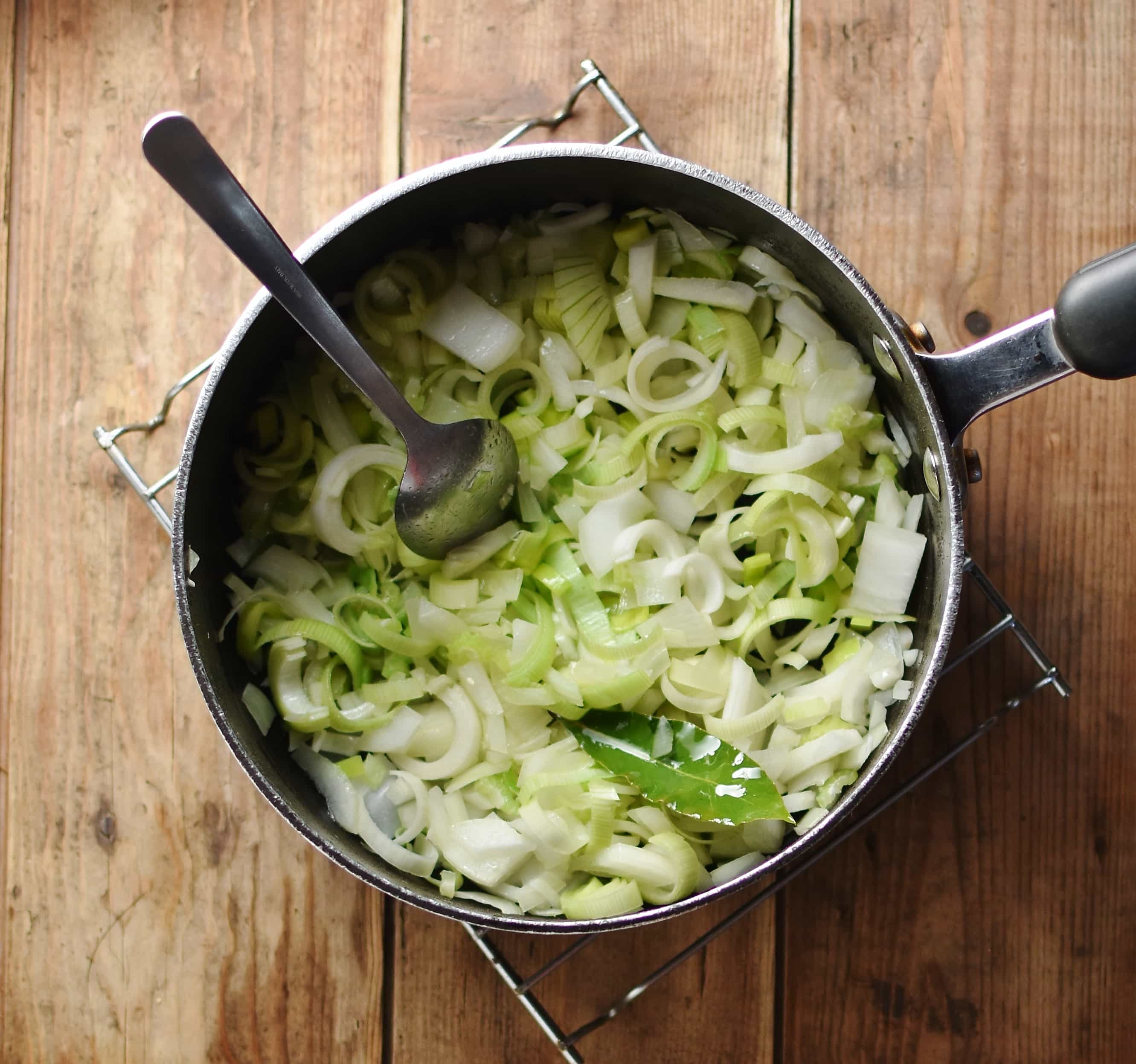 Chopped vegetables with spoon inside large pot.
