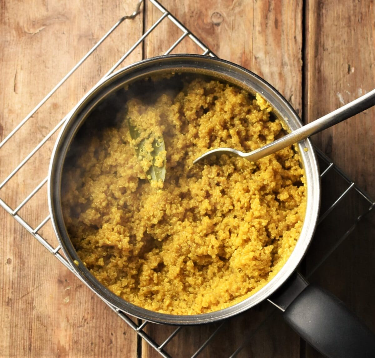 Curry quinoa in pot with spoon.