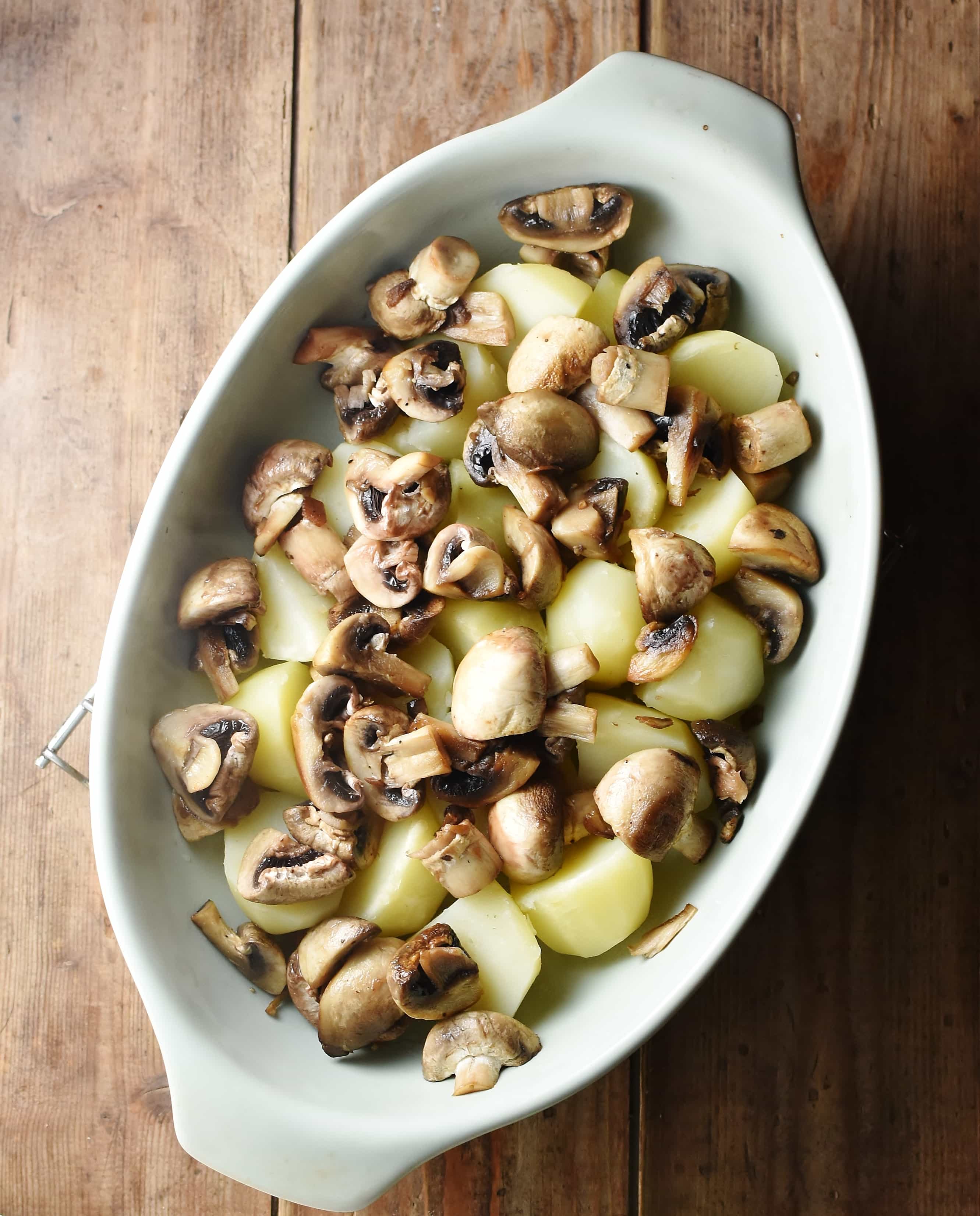 Potato pieces and chopped mushrooms in oval dish.