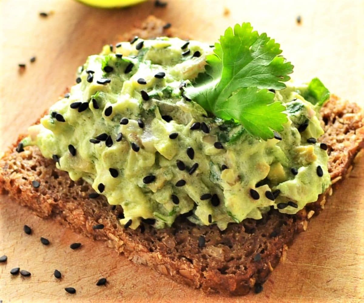 Close-up view of avocado mixture on top of rye bread.