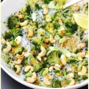 Close-up view of bean thread noodles salad with broccoli and cashews in white bowl.