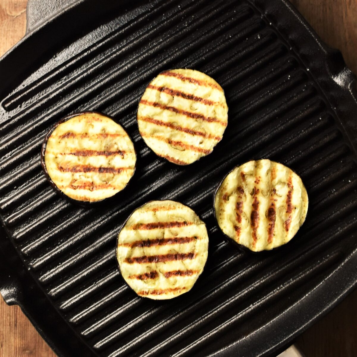 4 grilled eggplant slices in griddle pan.