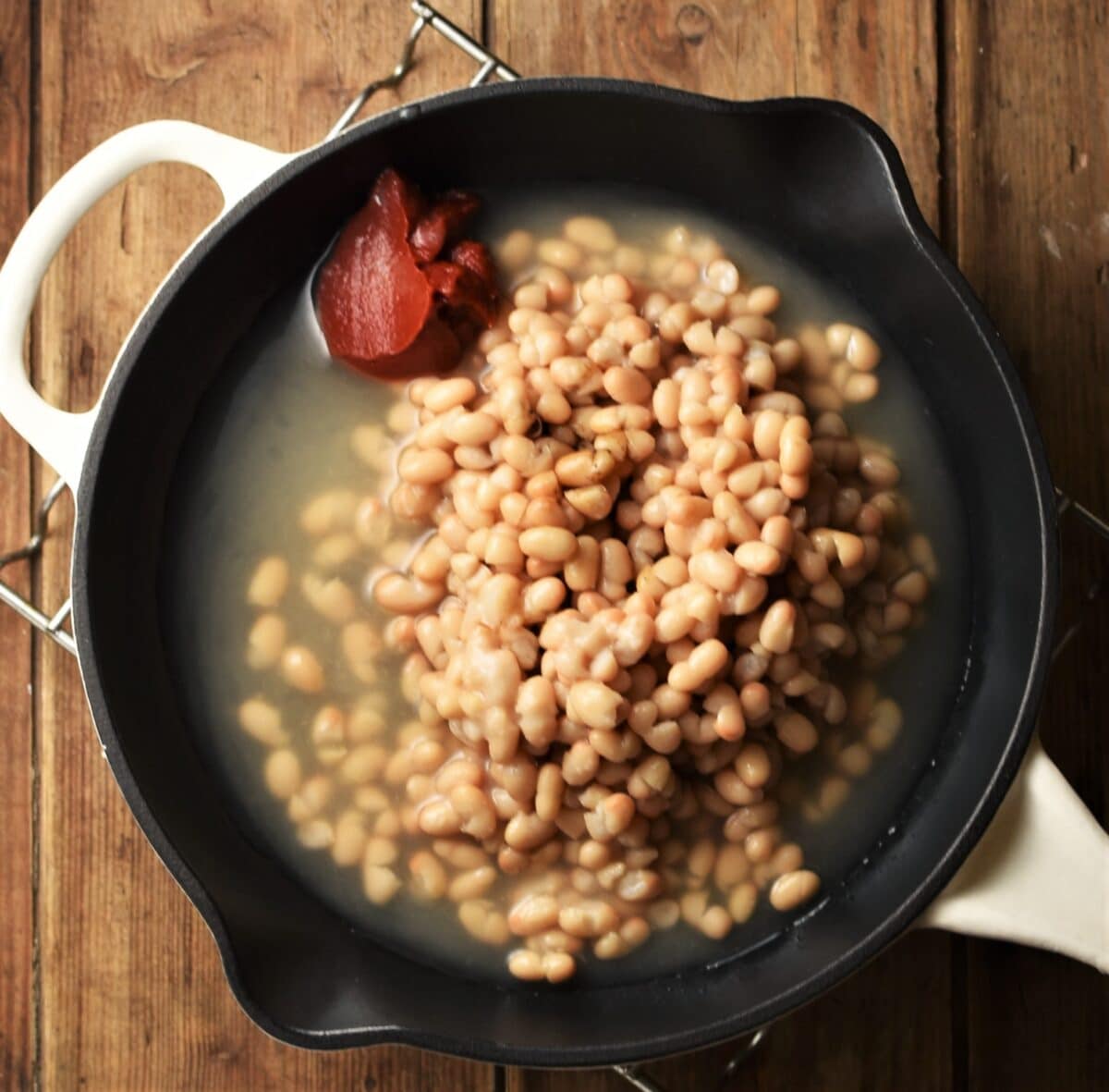 Beans with tomato paste in skillet.