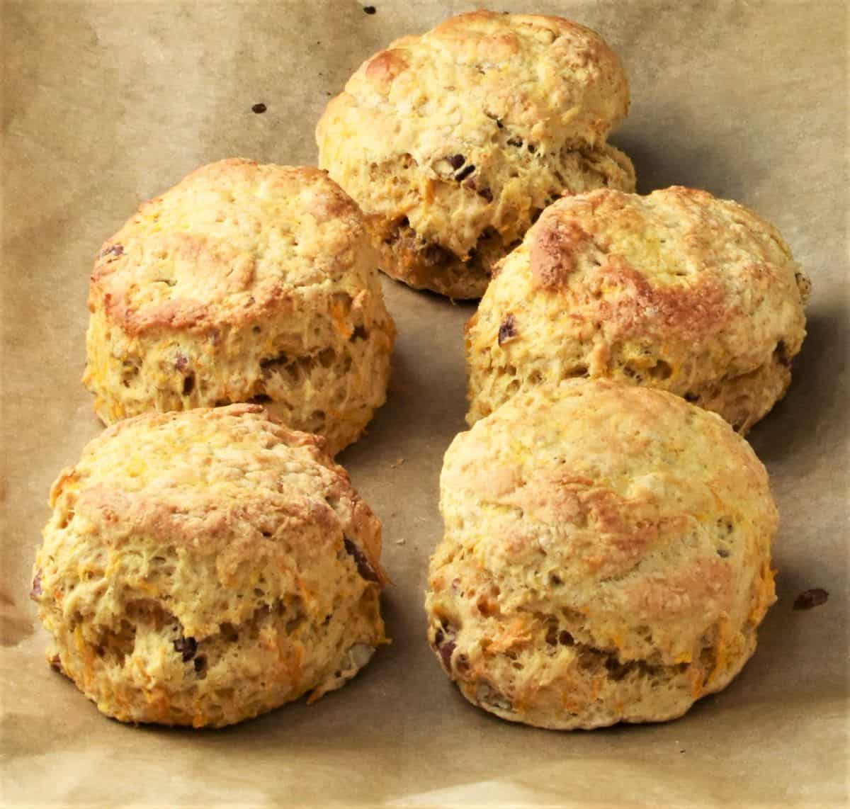 Side view of 5 ready made carrot scones on top of parchment.