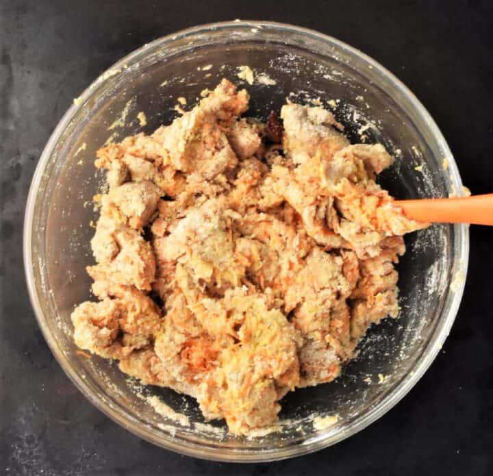 Making carrot scones dough in bowl with orange spoon.