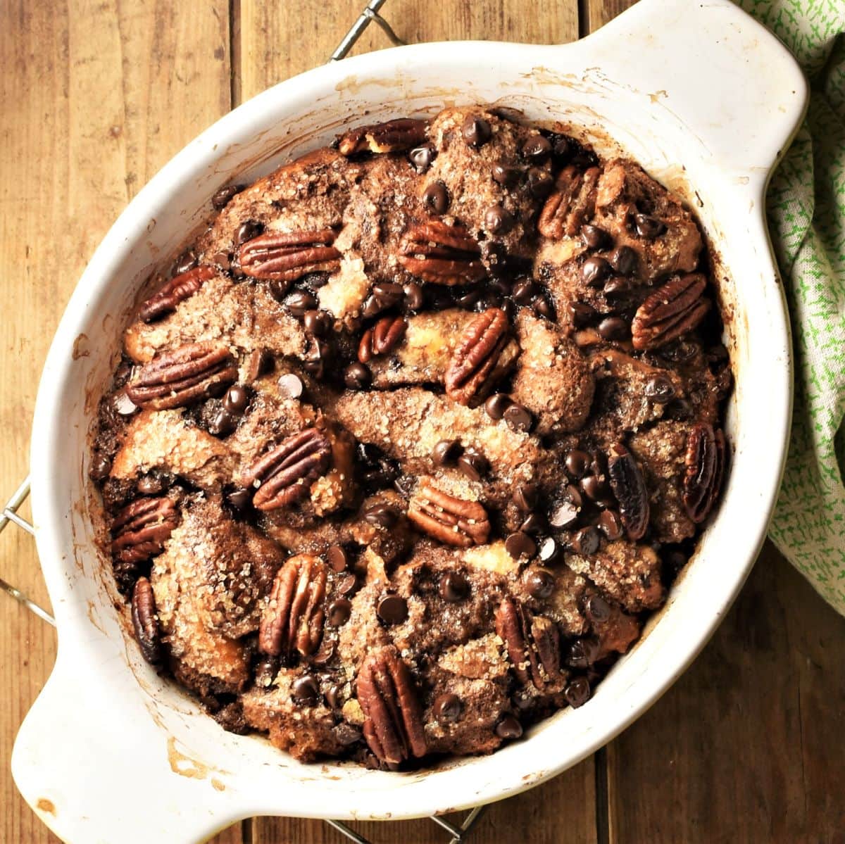 Chocolate french toast casserole with chocolate chips and pecans in white oval dish.