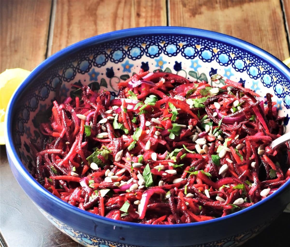 Side view of raw beetroot salad in blue bowl.