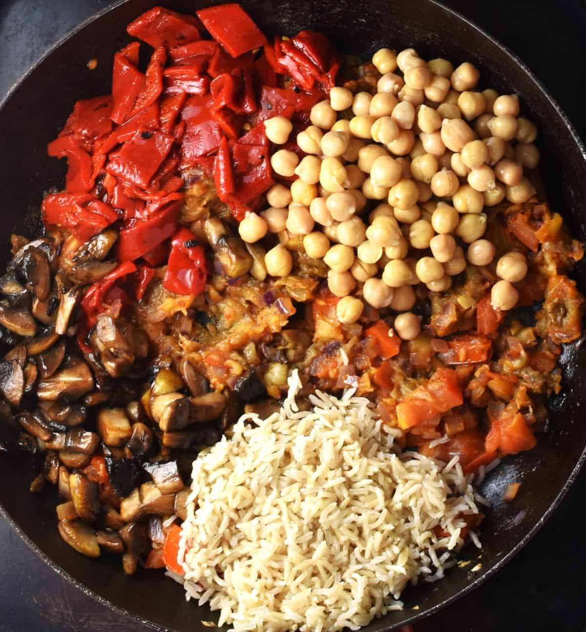 Rice, mushrooms, chickpeas, peppers and eggplant in large pan.