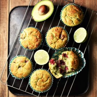 Avocado muffins with limes and fresh avocado on top of rack.