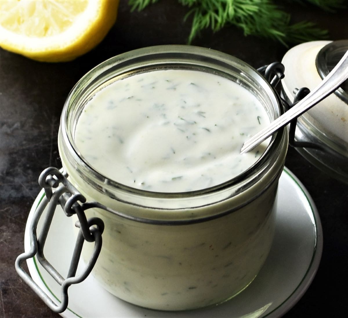 Close-up view of ranch dressing in open jar with spoon.