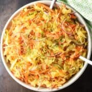 Top down view of sauerkraut salad in white bowl with 2 spoons.