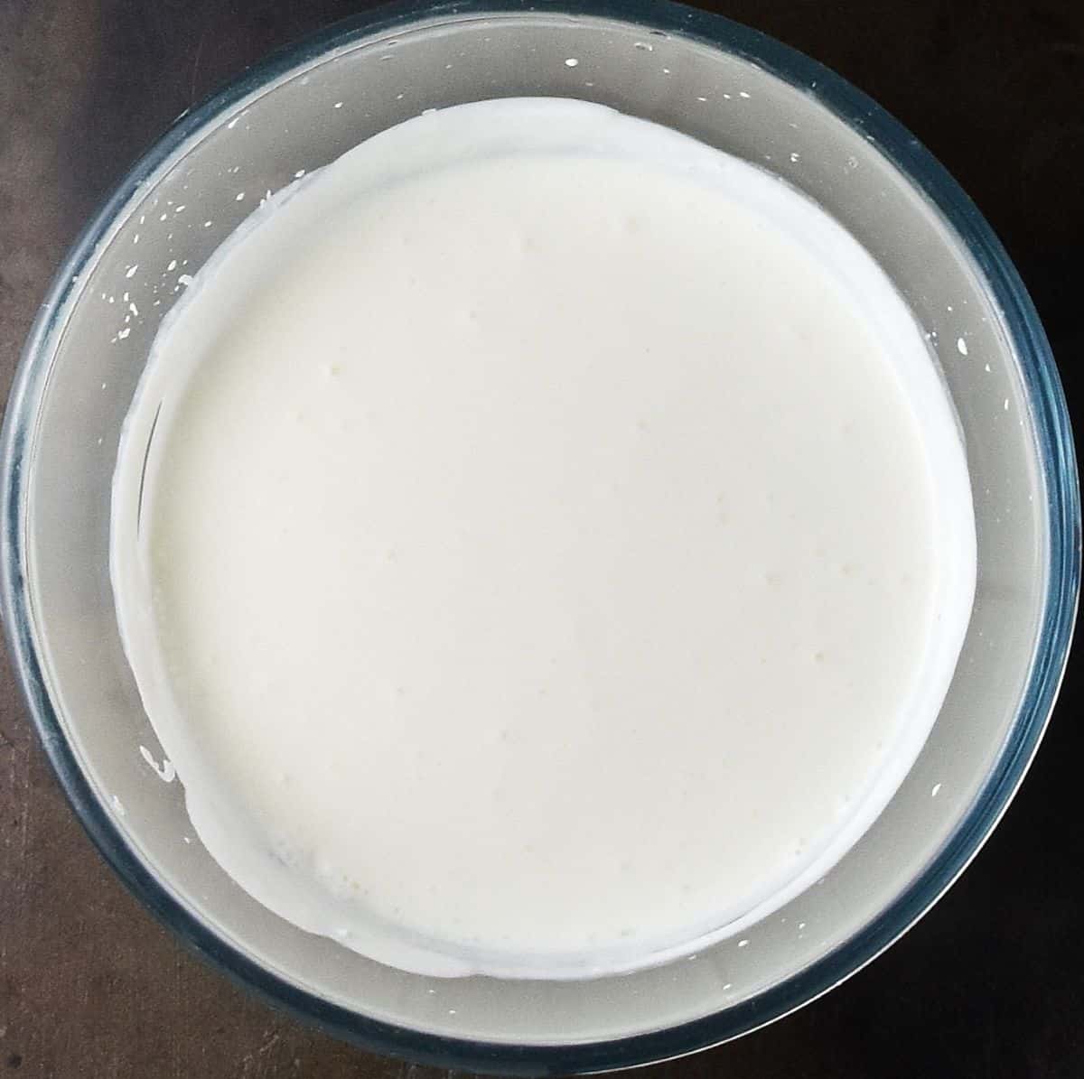 Top down view of creamy ranch dressing in glass bowl.