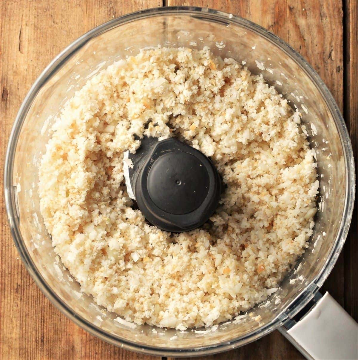 Crumbly bread mixture in food processor bowl.