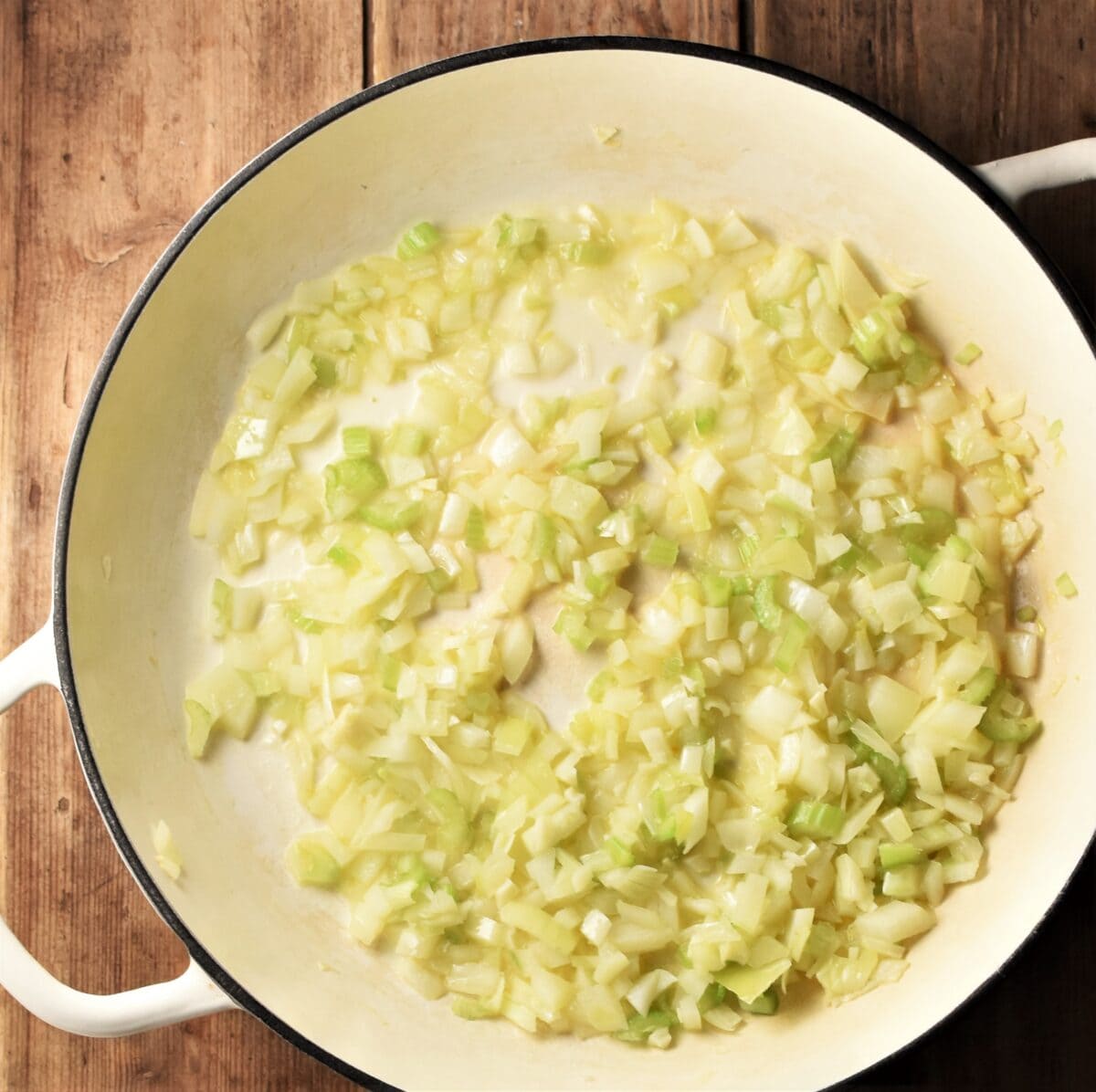 Chopped onion and celery in large white shallow pan.