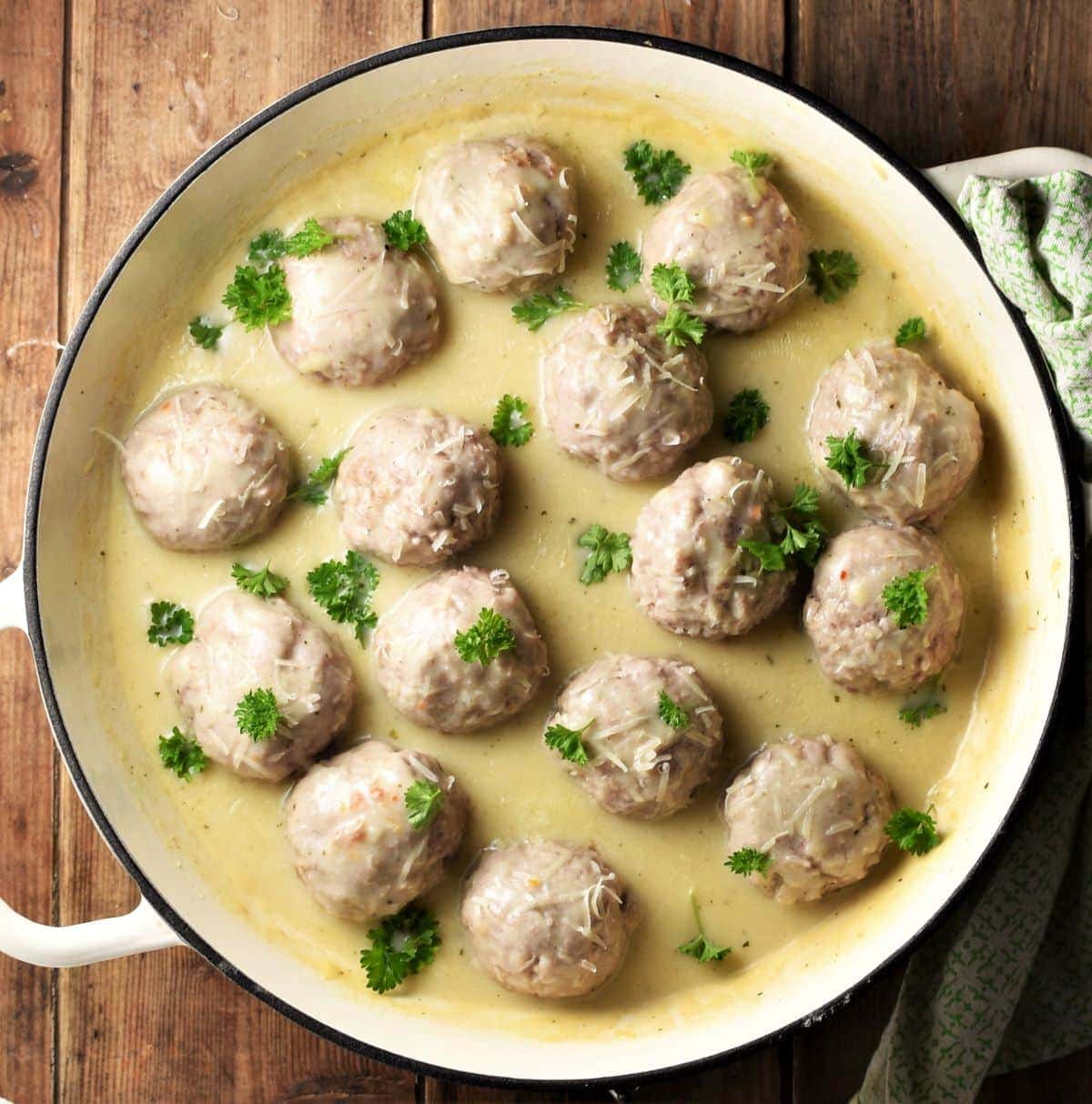 Meatballs in creamy sauce with parsley in large shallow pan.