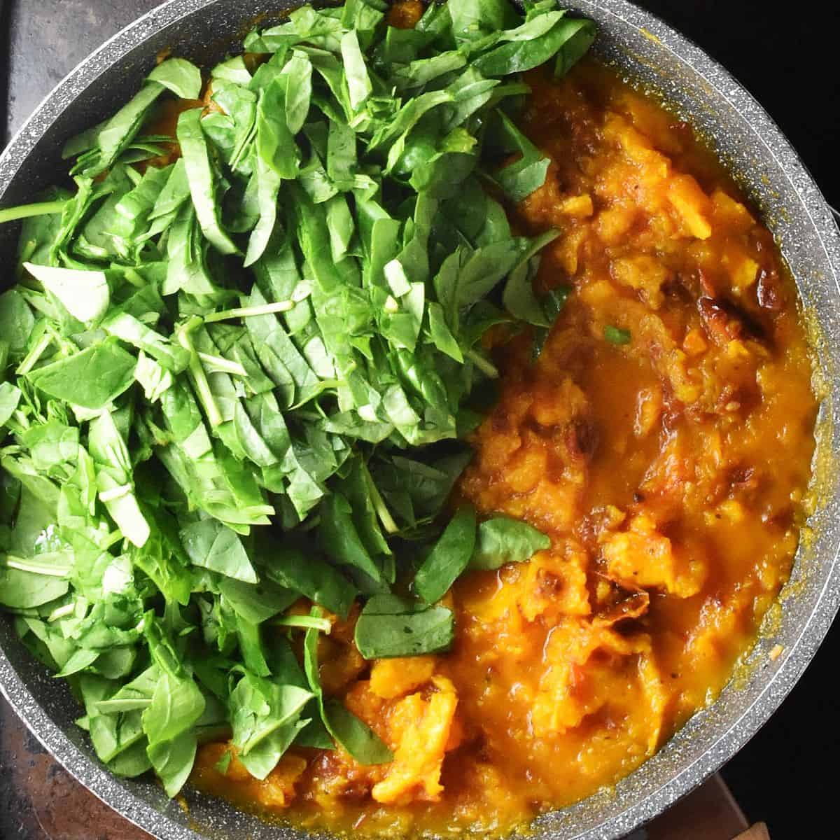 Chopped spinach and pumpkin sauce in large pan.