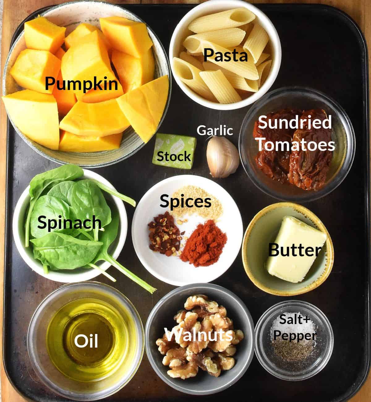 Top down view of roasted pumpkin pasta ingredients in different size and colour dishes.