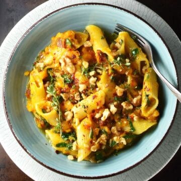 Top down view of roasted pumpkin pasta in blue bowl with fork.