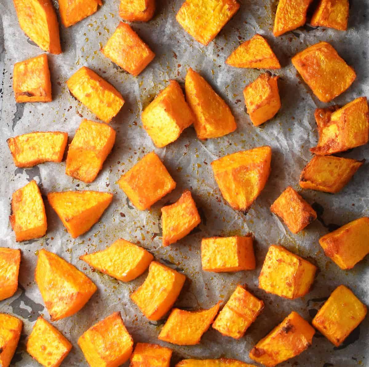 Roasted pumpkin pieces on parchment.