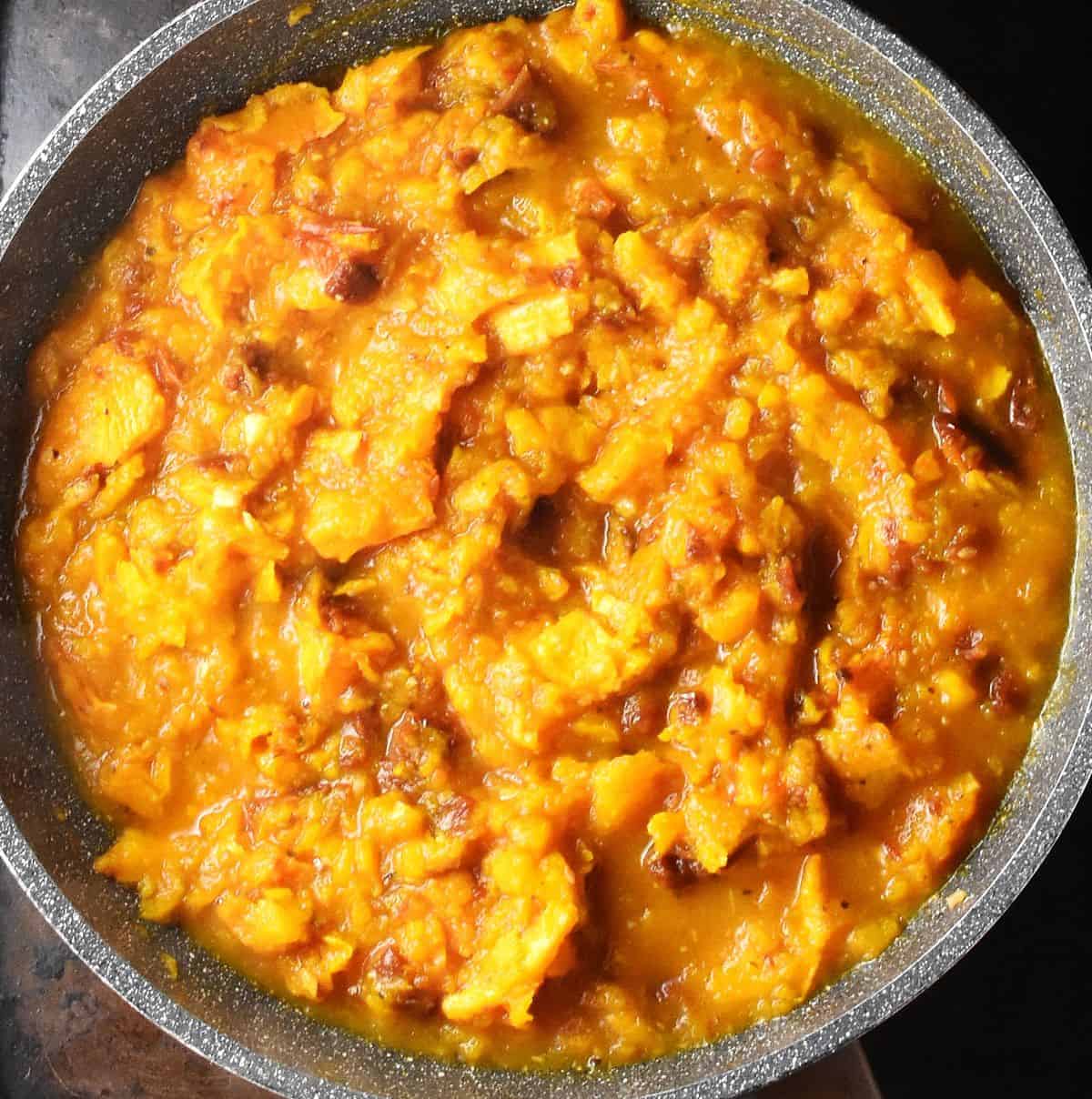 Top down view of rustic pumpkin sauce in large, grey pan.