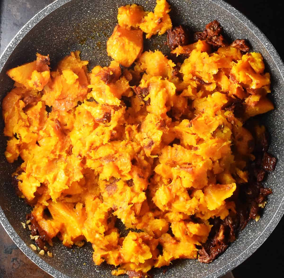 Thick mixture of roasted pumpkin in large pan.
