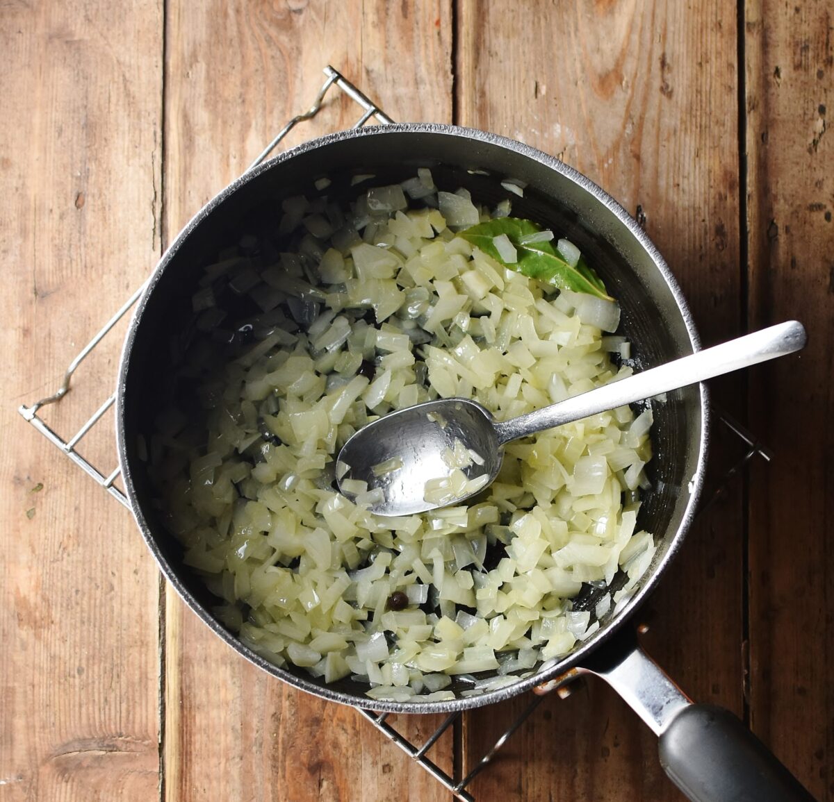 Chopped onions in large pot with spoon. 