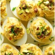 Top down view of smoked salmon deviled eggs garnished with chives and pistachios.