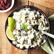 Turkey and avocado creamy salad with lime wedges in purple bowl with spoon.