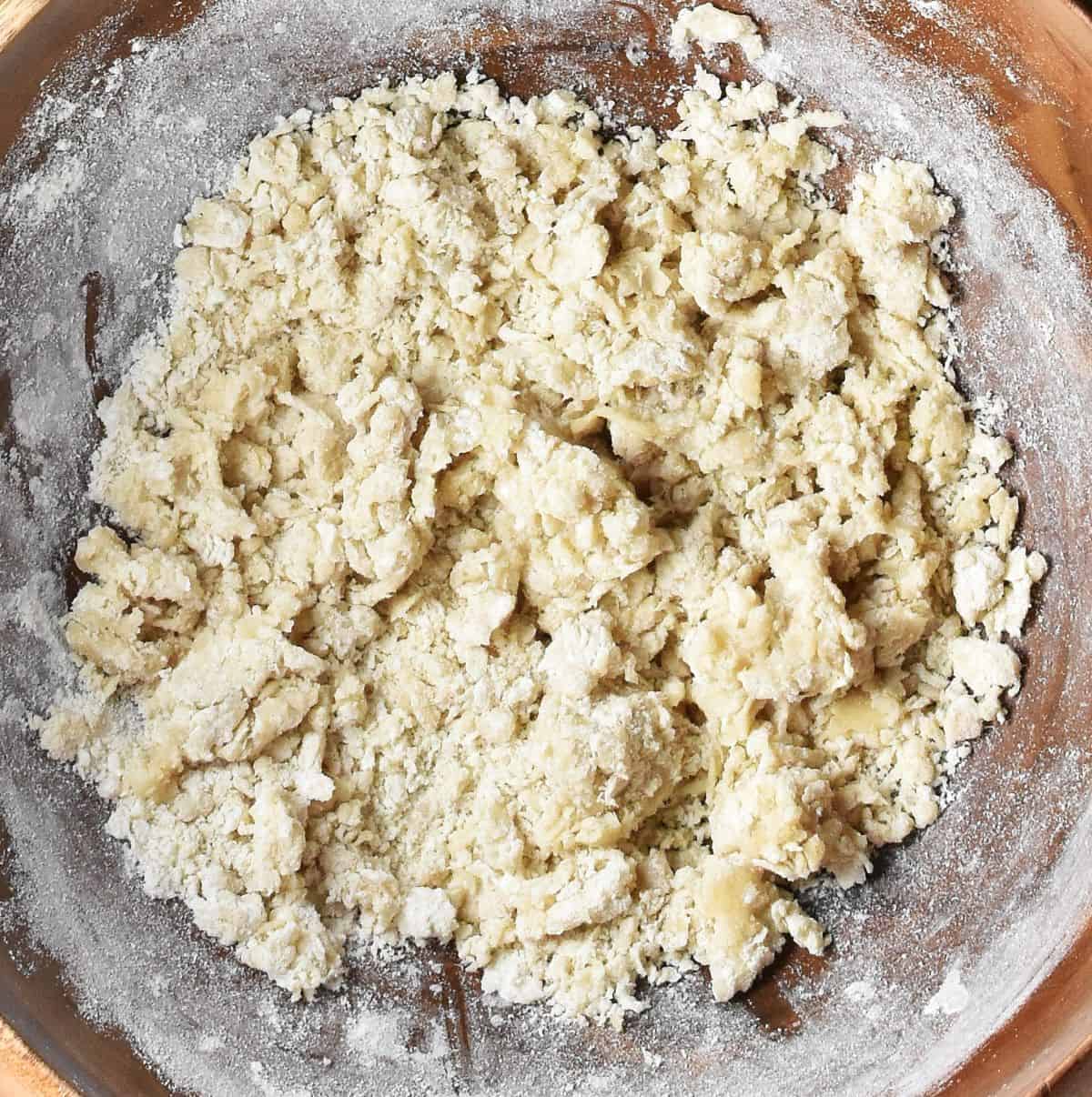 Rough dough mixture for Polish pierogi in wooden bowl.