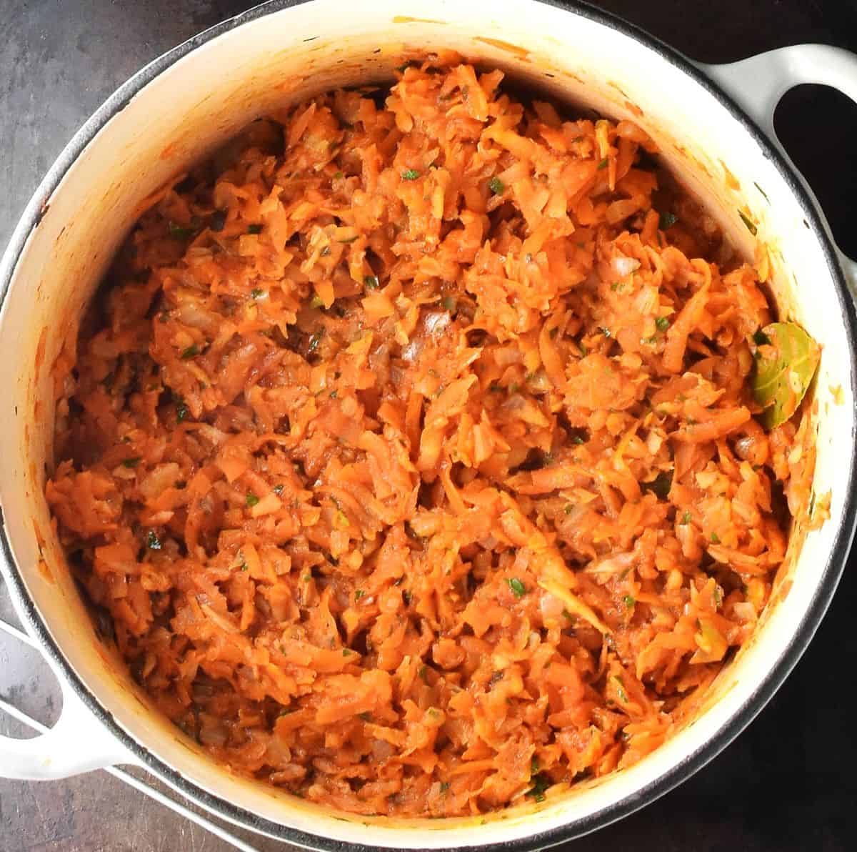Shredded vegetable stew in large, white pot.