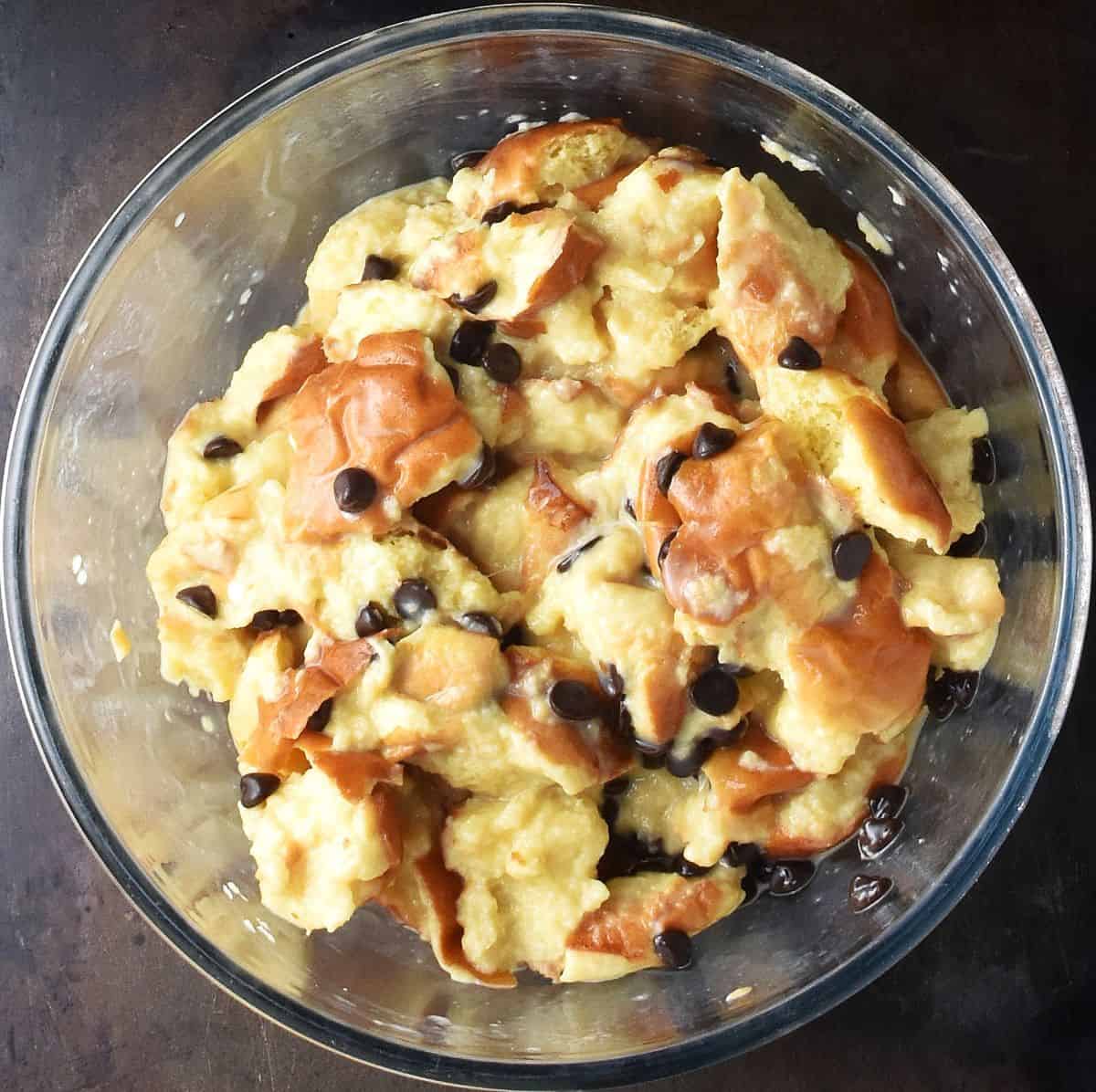 Top down view of french toast muffin mixture with chocolate chips in glass bowl.
