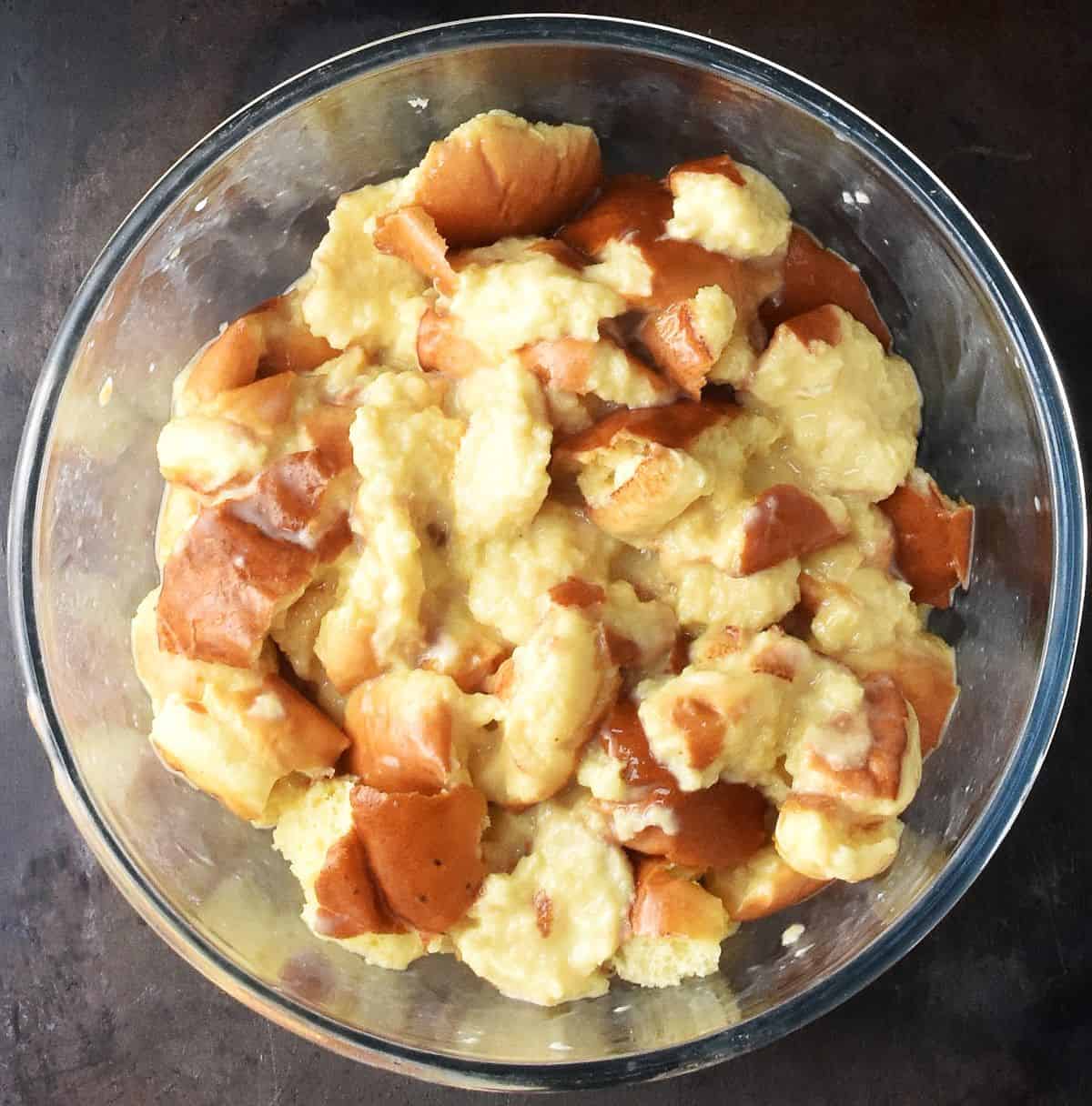 Brioche pieces soaked in egg mixture in large glass bowl.