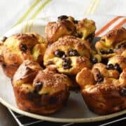 Side view of browned, baked french toast muffins on plate with cloth in background.
