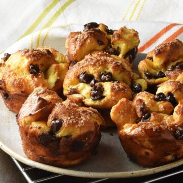 Side view of browned, baked french toast muffins on plate with cloth in background.