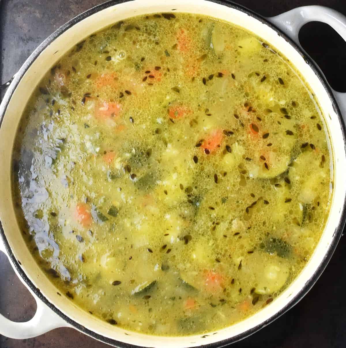 Thick, chunky zucchini soup in white pot.