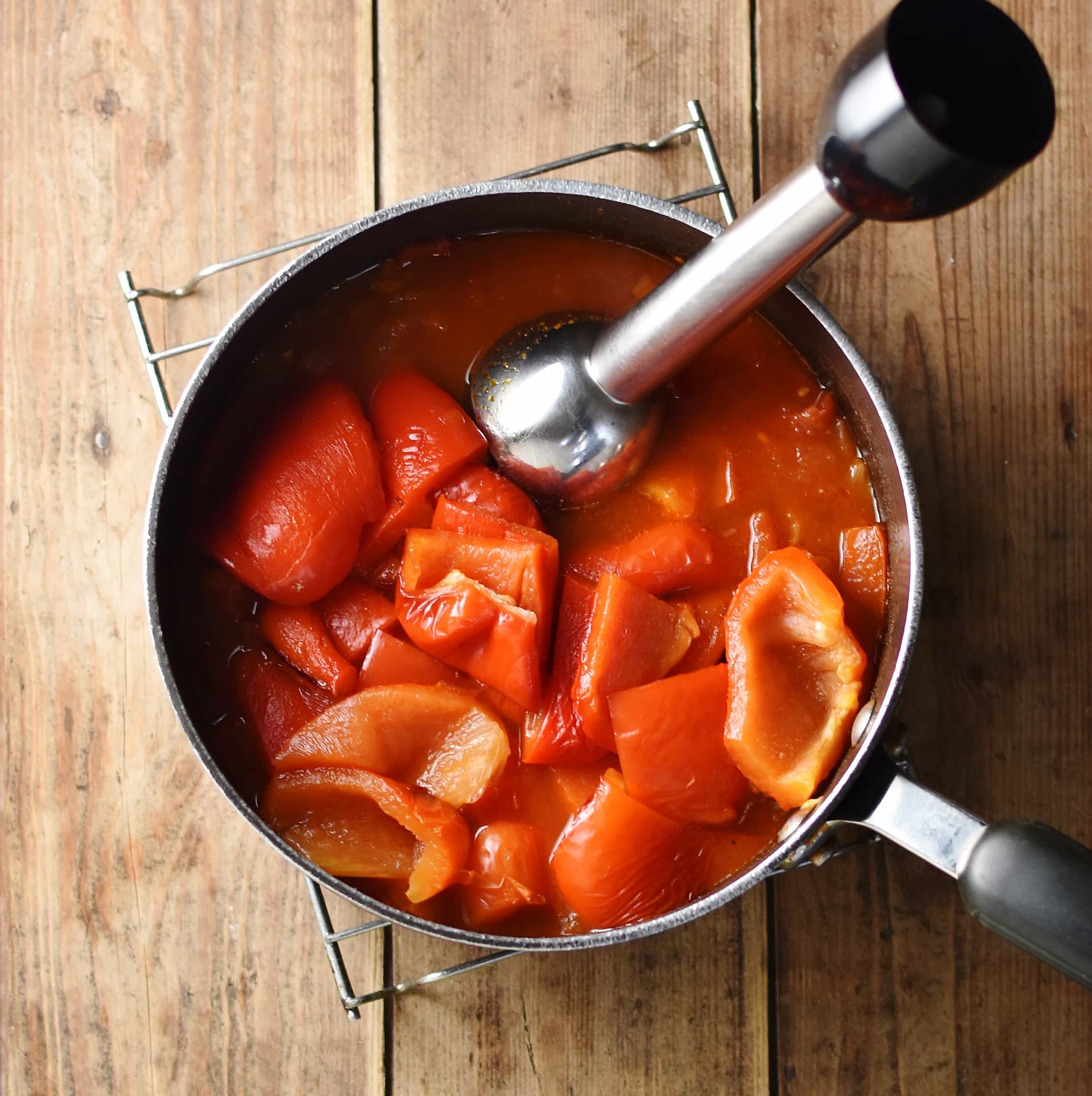 Roasted peppers and tomatoes in large pot with hand blender